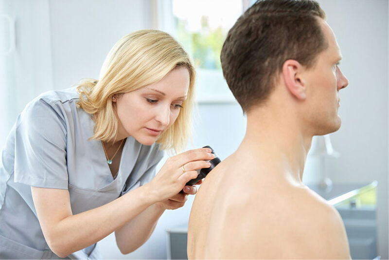 Dr. Jost untersucht den Rücken eines Mannes